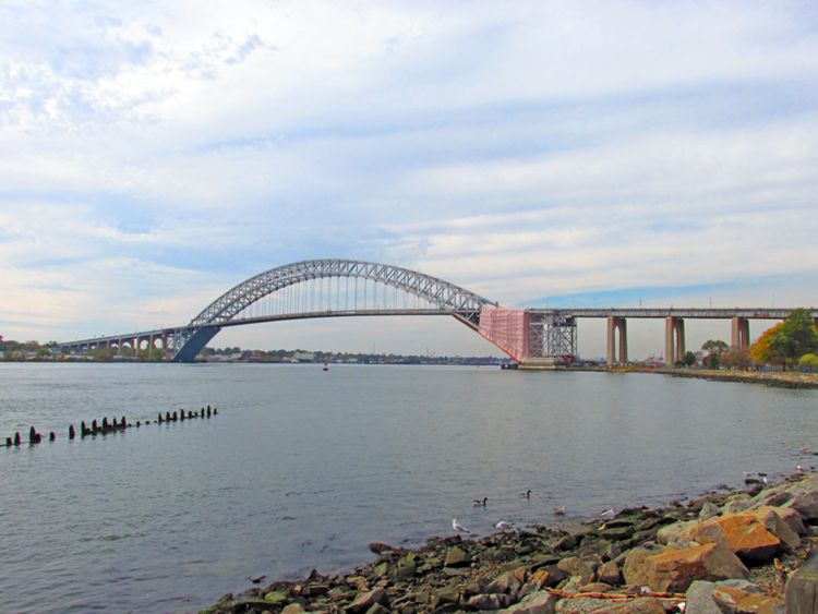 2013: Bayonne Bridge across the Kill von Kull, linking Bayonne (right) and Staten Island (left). (This is the fifth-longest steel arch bridge in the world.) Near here on September 6, 1609, a five-man survey party in a small boat started back to the Half Moon, the ship commanded by Henry Hudson, after venturing many miles from its anchorage. Later, First Mate Robert Juet recorded in his journal: "The Lands they told us were as pleasant with Grasse and Flowers, and goodly Trees, as ever they had seene, and very sweet smells came from them."<sup>1</sup> This is probably the first recorded account of how "New Jersey" appeared to the first Europeans to get that close. Over four hundred years later, this tidewater channel has become a main thoroughfare of the Port of New York and New Jersey, where millions of tons of cargo pass annually.