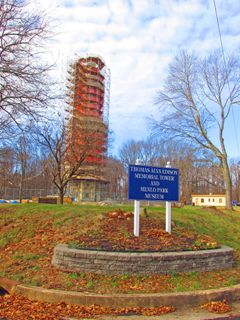 2013: View of the Menlo Park laboratory site today. A tower, commemorating Edison's laboratory, was built on the site in 1937; it is currently undergoing restoration. Just behind the sign is the outline of the foundation of Edison's private office building, where he kept his research notebooks. Outgrowing the facilities he had built here, Edison moved his operations to West Orange, New Jersey, in 1887. That site is now managed by the National Park Service.